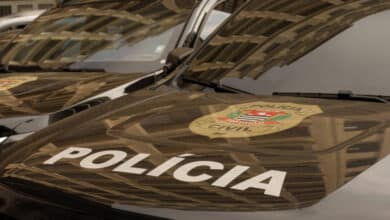 A imagem mostra a parte frontal de veículos da Polícia Civil, com o emblema da polícia visível. O capô dos carros é preto e apresenta a palavra