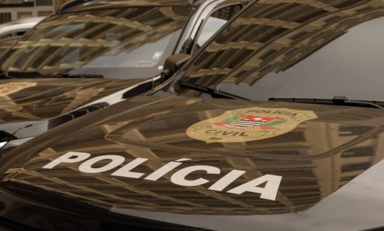 A imagem mostra a parte frontal de veículos da Polícia Civil, com o emblema da polícia visível. O capô dos carros é preto e apresenta a palavra