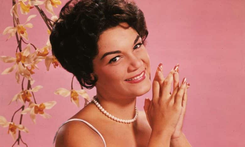 Studio portrait of American singer Connie Francis wearing a lavender and white spaghetti-strap dress.