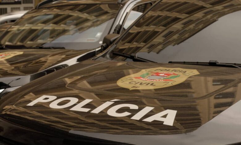 A imagem mostra a parte frontal de veículos da Polícia Civil, com o emblema da polícia visível. O capô dos carros é preto e apresenta a palavra
