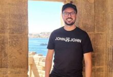 Um homem está posando em uma abertura de pedra, com vista para um corpo d