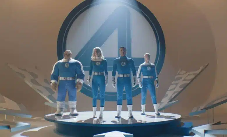 A imagem mostra quatro personagens em trajes azuis, em uma plataforma circular. Eles estão posicionados em uma pose heroica, com um grande símbolo do Quarteto Fantástico ao fundo. A iluminação destaca os personagens, criando um efeito dramático. O ambiente é moderno e minimalista, com elementos gráficos ao redor.