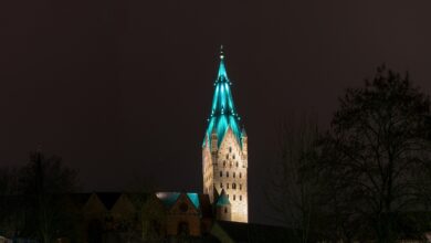 Der Turm des Paderborner Domes wird vor einem dunklen Nachthimmel farbig angestrahlt.